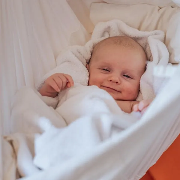 Lächelndes Baby in einer Hängematte im Hotel Babymio