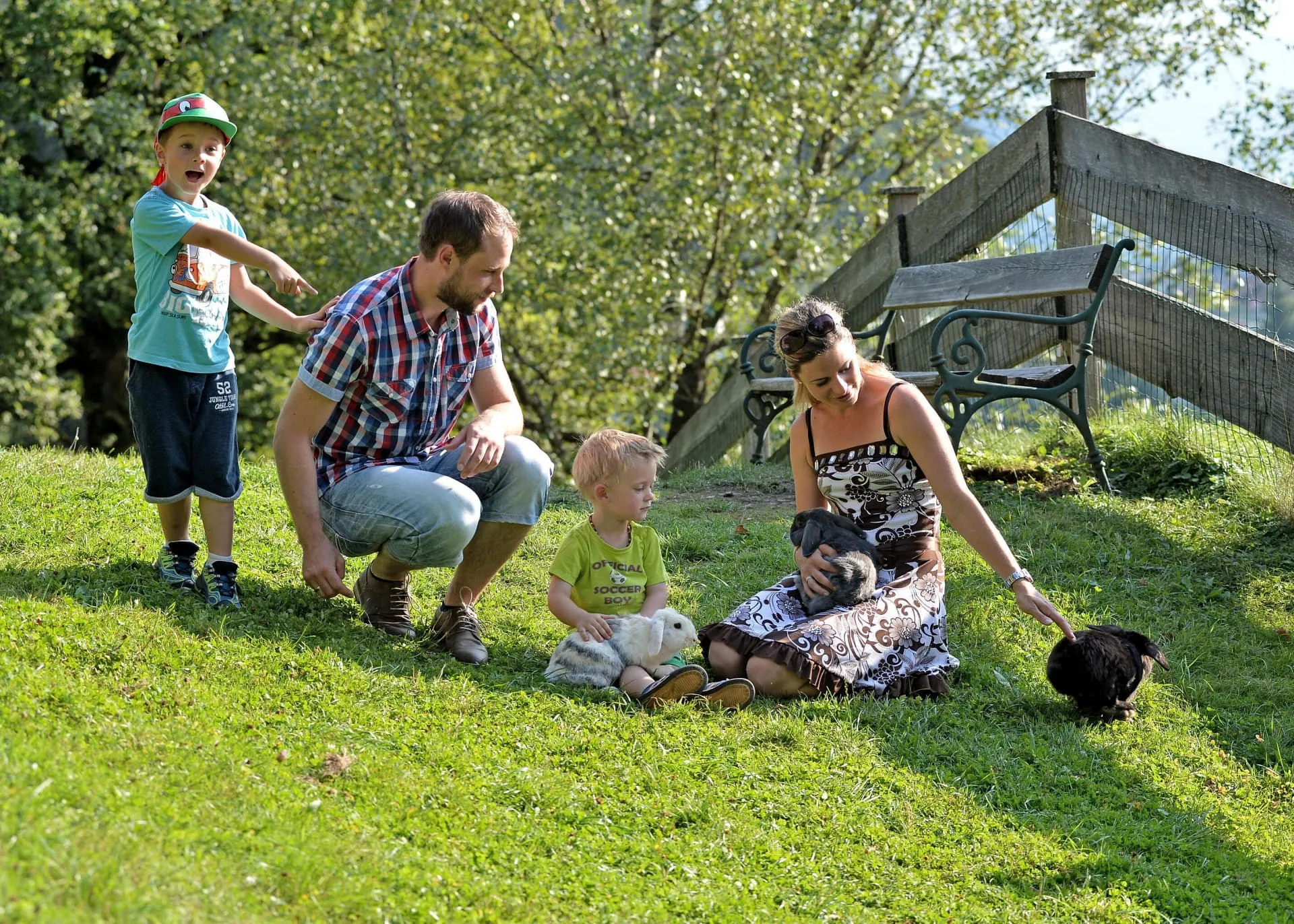 Familie mit zwei Kindern spielt mit Kaninchen auf der Wiese