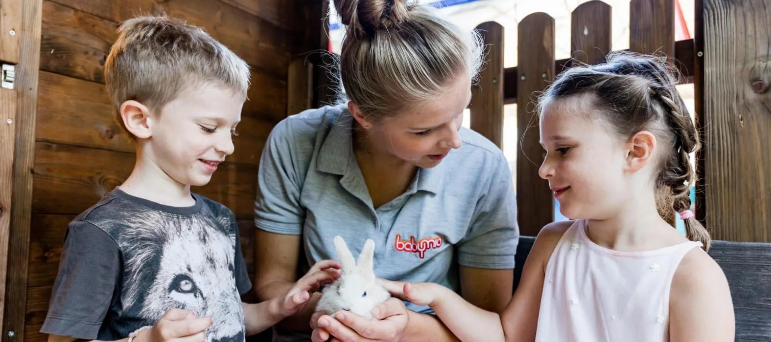 Betreuerin vom Hotel zeigt Kindern ein Kaninchen und sie streicheln es