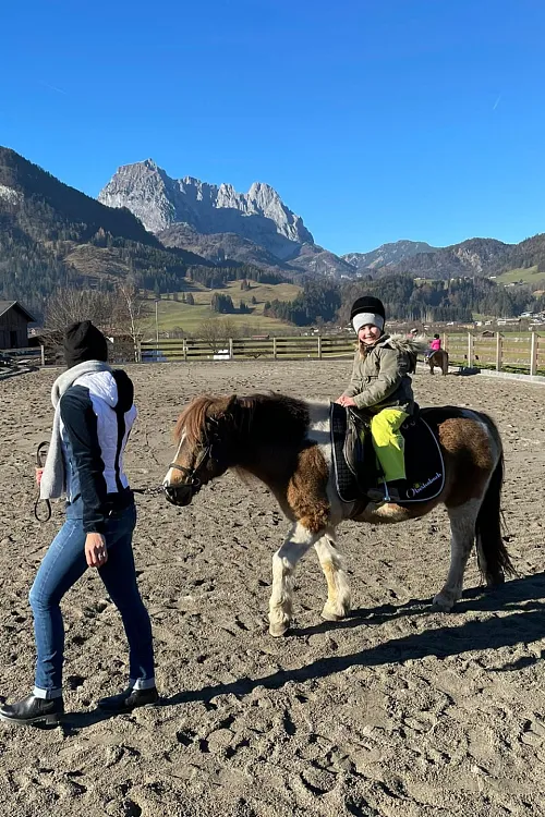 Kind reitet Pony vor Kitzbüheler Bergkulisse in Tirol
