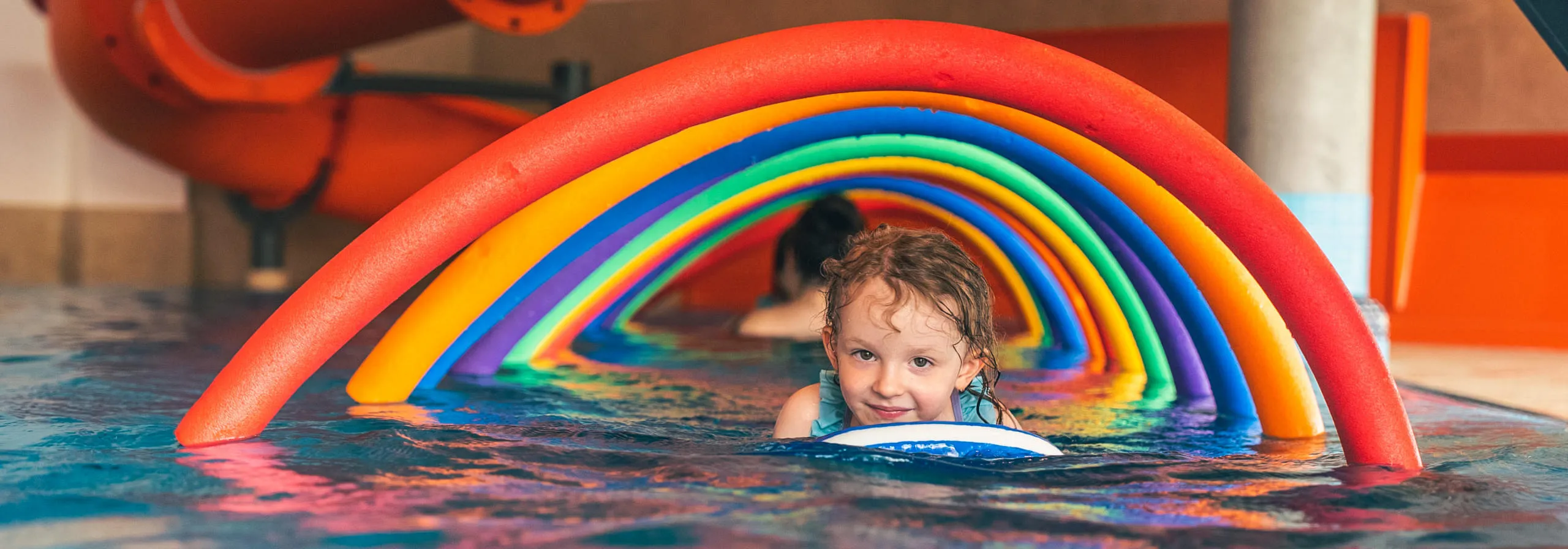 Außenansicht Hotel Babymio: Pool, Garten und Spielplatz im Sommer