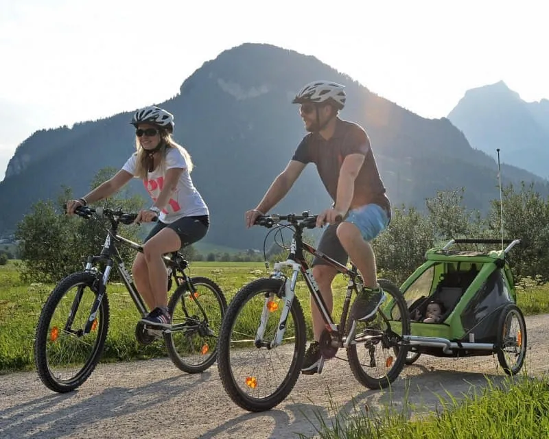 Familie beim Radfahren mit Kinderanhänger und Baby im Kitzbüheler Tal