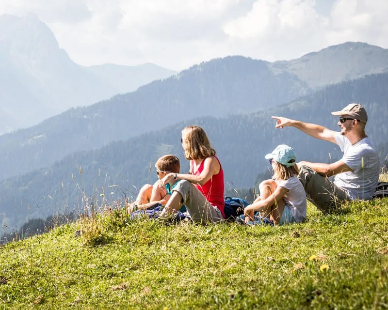 Familie genießt Bergblick auf die Kitzbüheler Alpen von einer Wiese