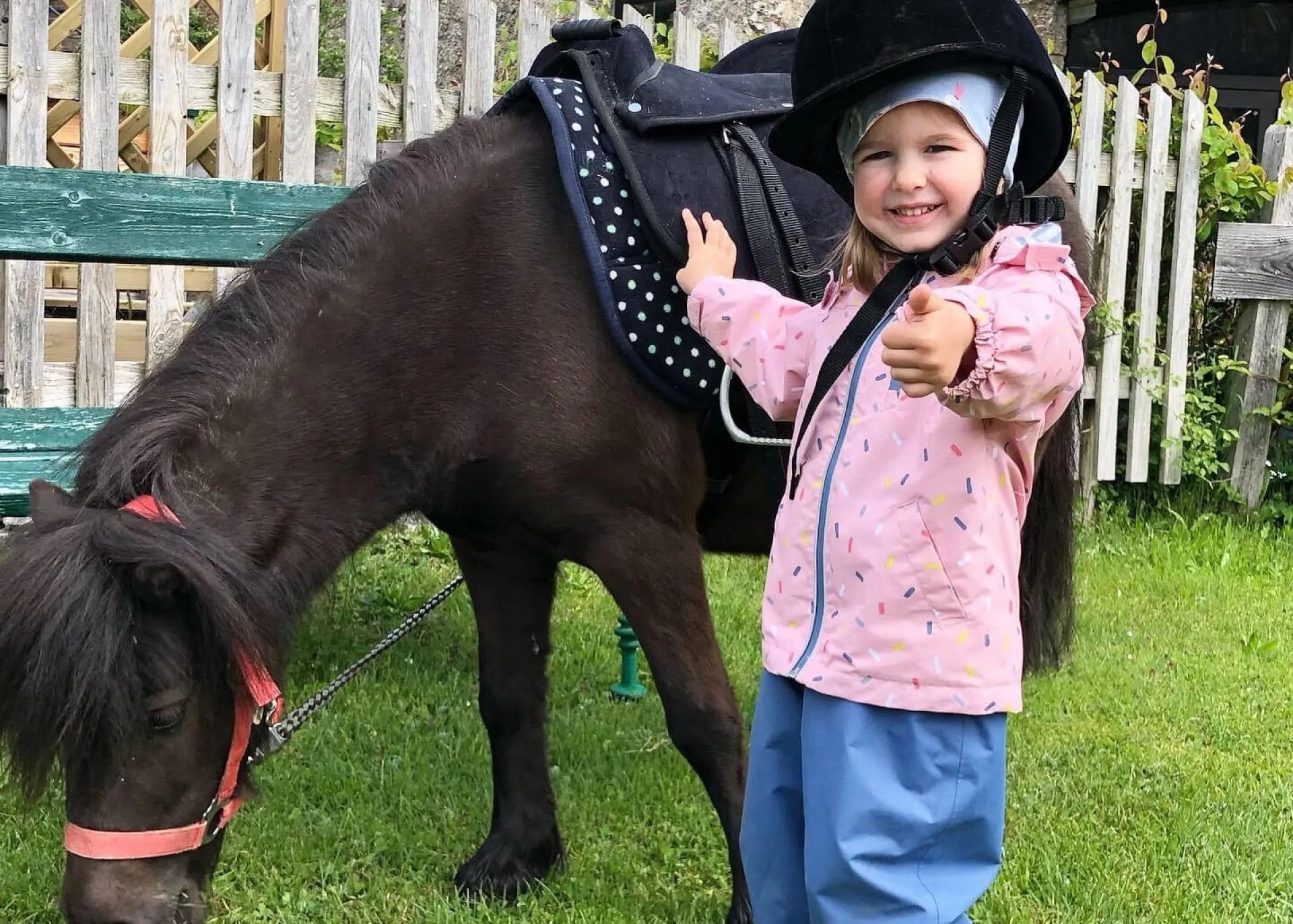 Lachendes Kleinkind steht vor Pony