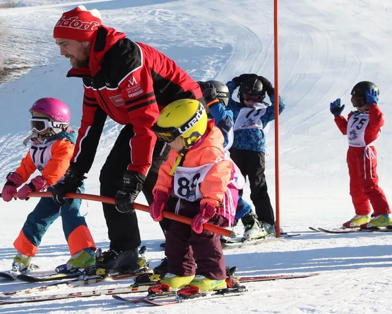 Kinder-Skikurs mit Skilehrer und Kindern im Mini-Skiclub