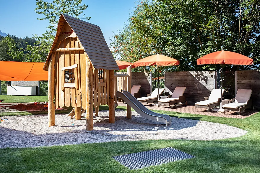 Hotelgarten mit Liegestühlen, Holz-Spielhaus und Rutsche